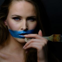 Frau mit blauer Farbe am Mund und Pinsel